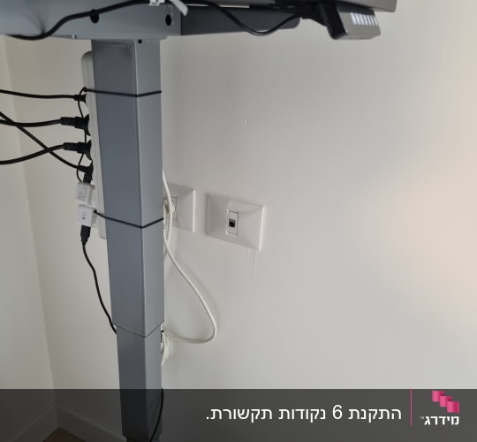 שולחן עבודה עם כבלים מחוברים לשקעי חשמל